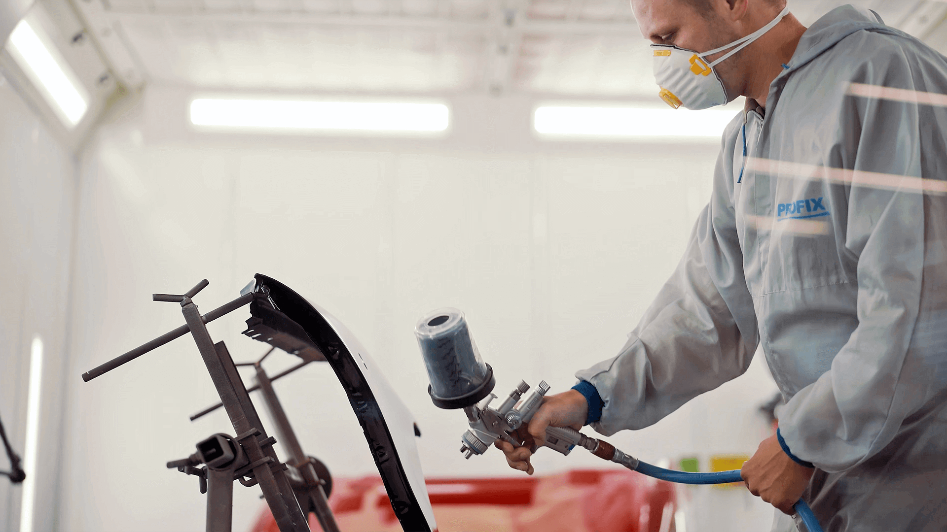 painting the car part with a spray gun 
